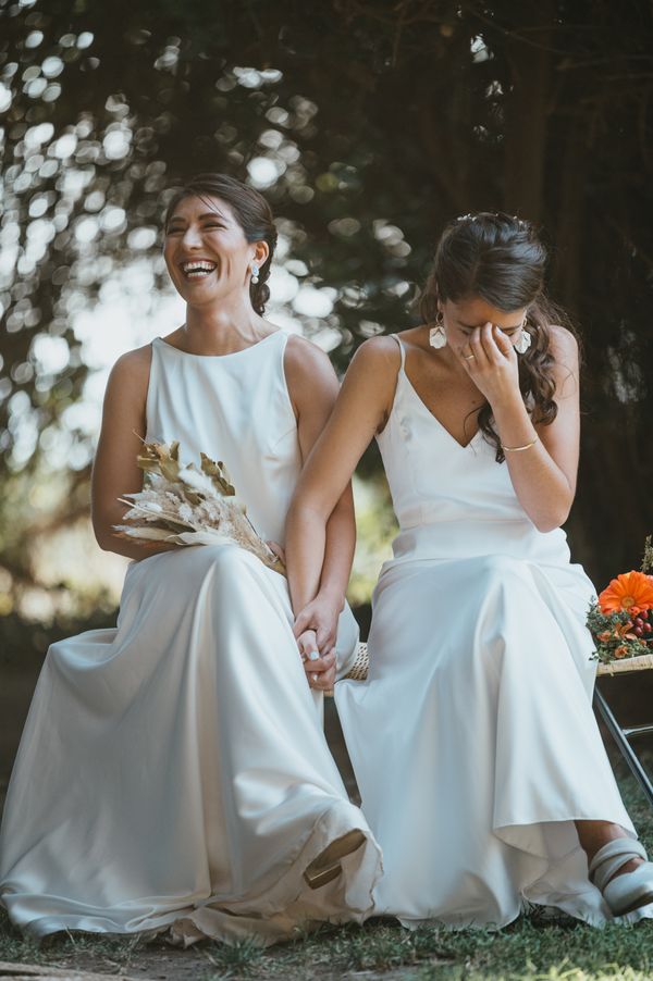 Two brides laughing together on their wedding day