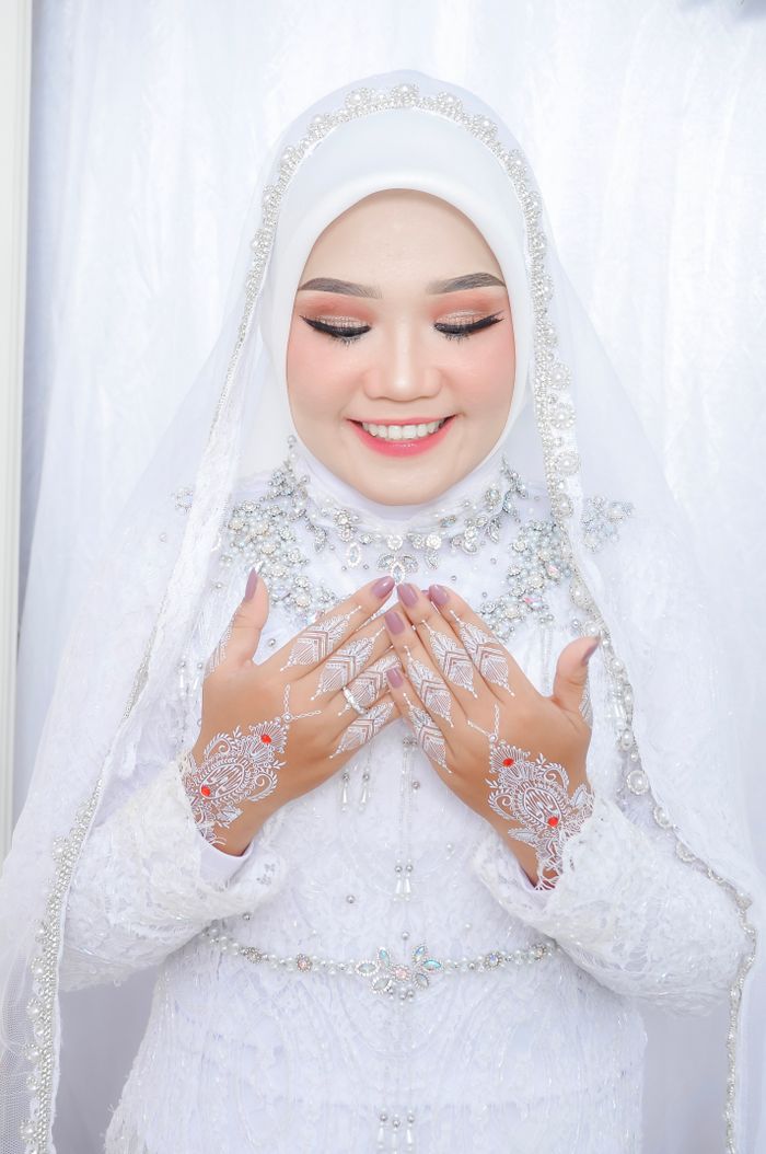 Smiling bride in a white hijab with henna