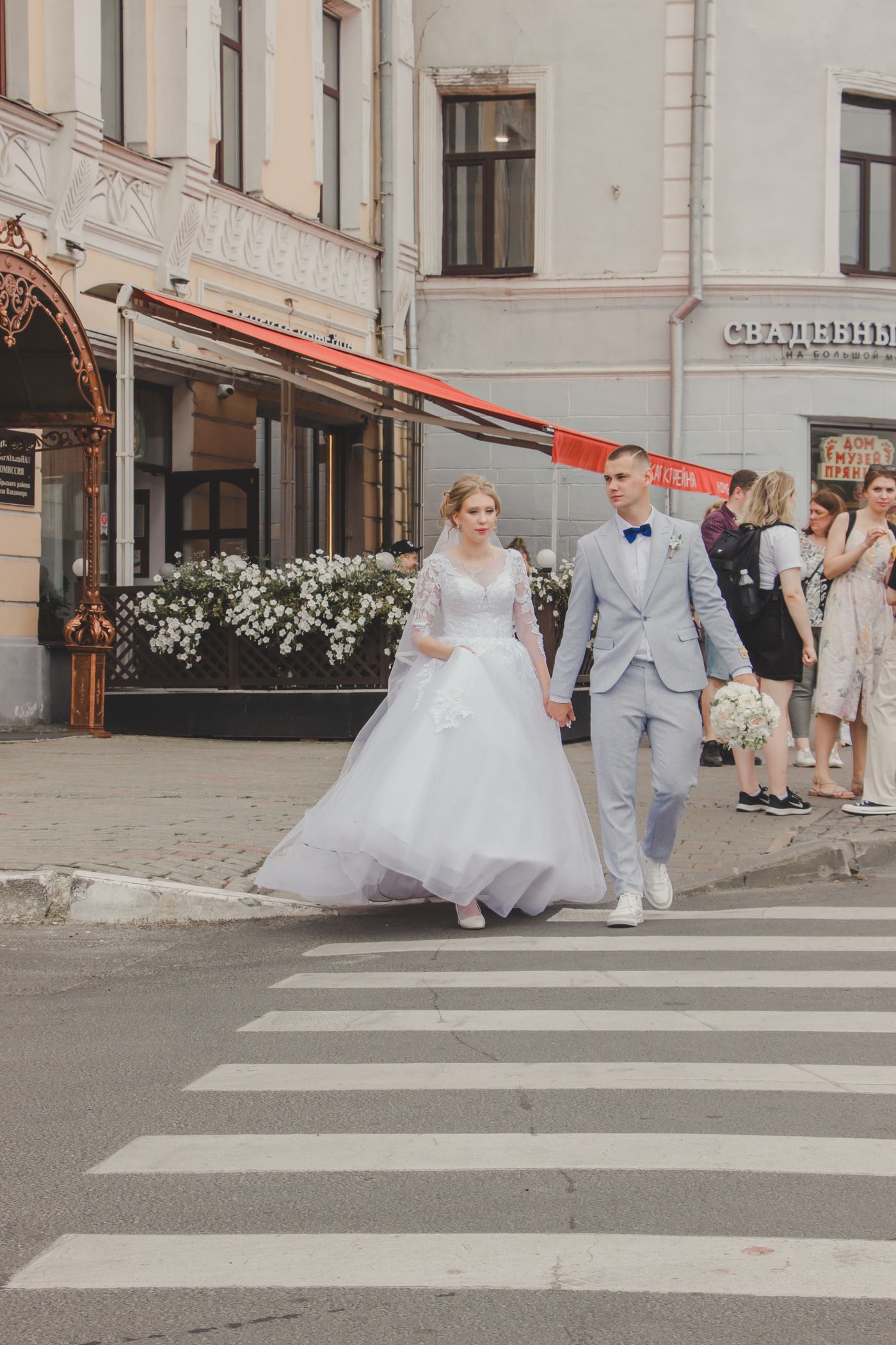 Bride and groom walking hand in hand across a city street